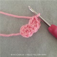 the crochet hook is being used to make a heart - shaped piece of yarn