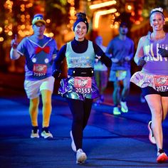 two women running in a half marathon with other runners behind them at night time,