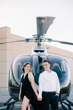 a man and woman standing in front of a helicopter