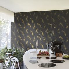 the kitchen counter is white with black and gold wallpaper