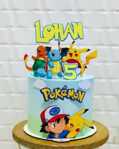 a pokemon themed birthday cake on a wooden table with white brick wall in the background