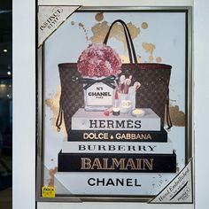 an advertisement for a chanel handbag with flowers and other items on display in a window