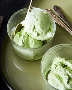 two bowls filled with green ice cream on top of a plate next to silverware