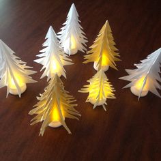 white paper christmas trees on a wooden table with lights in the shape of pine trees