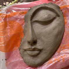 a clay face sitting on top of a plastic bag