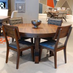 a wooden table with four chairs around it in a room filled with tables and chairs