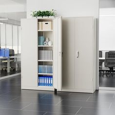 a white cabinet with books and files in an empty office space next to a computer desk