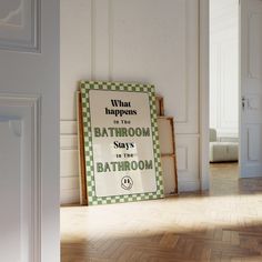 a bathroom sign on the floor in front of an open door with white walls and wood floors