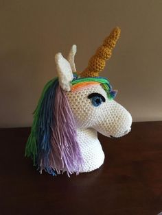 a crocheted unicorn head sitting on top of a wooden table