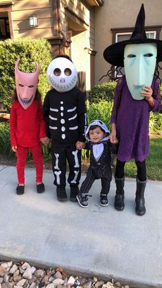 three children in halloween costumes standing on the sidewalk