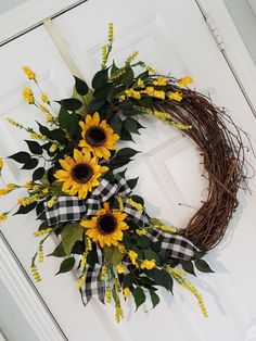 a wreath with sunflowers and greenery on the front door