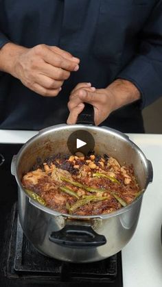 a man cooking food in a pot on top of a stove with the lid open