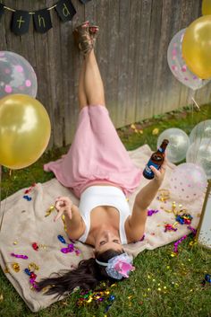 a woman laying on the ground with balloons and confetti