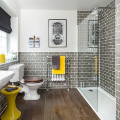 a bathroom with gray and white tile, wood flooring and yellow accents on the walls