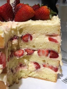 a close up of a cake with strawberries on top and one slice cut out