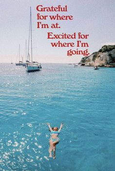 a woman swimming in the ocean with a sailboat behind her and an advertisement that reads grateful for where i'm at