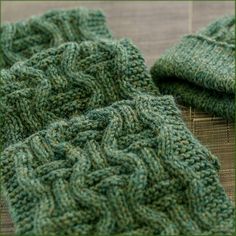 two green knitted scarves sitting on top of each other