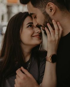 a man and woman embracing each other with their hands on their foreheads while they are looking into the distance