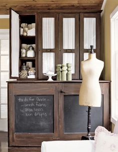 a mannequin is standing in front of an old fashioned cabinet with glass doors