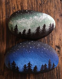 two painted rocks sitting on top of a wooden table