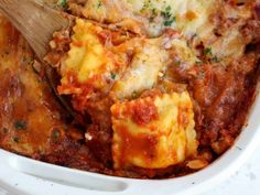 a casserole dish with meat, cheese and sauce is being stirred with a wooden spoon