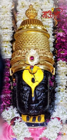 the head of an idol is surrounded by flowers and garlands in gold, black, and white colors