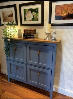 a blue dresser with drawers and pictures on the wall