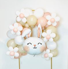 a bunch of balloons that are in the shape of a bunny head and flowers on sticks