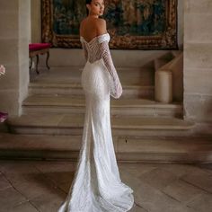 a woman in a white wedding dress is standing on some steps and looking off into the distance