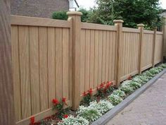 a wooden fence with flowers growing on the sides and in between it is a brick sidewalk