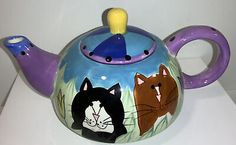 a teapot with three cats painted on it