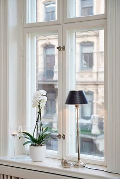 a window sill with a lamp and flowers on it in front of a window