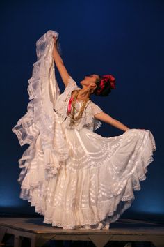 a woman in white dress dancing on stage