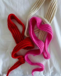 three different colored yarns laid out on a white sheet, one pink and one red