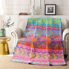 a living room with a white chair and a colorful blanket on the couch in front of it