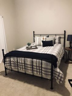 a bed with black and white comforter in a bedroom next to a lamp on a table