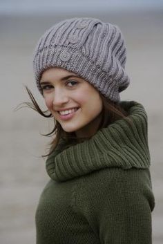 a smiling woman wearing a gray hat and green sweater