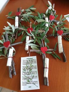 several branches with candles and paper hearts attached to them, on a table next to a piece of paper