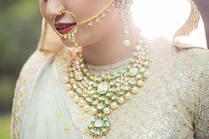 a woman in a white and gold outfit with jewelry on her face, wearing a nose ring