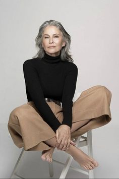 an older woman sitting on a chair with her legs crossed