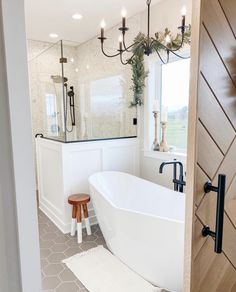 a white bath tub sitting inside of a bathroom next to a wooden door and window