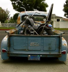 an old blue truck with a motorcycle in the back