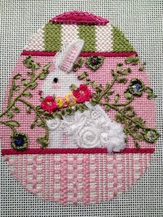 a pink and white cross stitched ornament with a bunny in the center