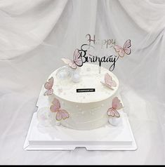 a white birthday cake with pink butterflies on it and the words happy birthday written on top