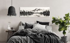 a bedroom with a large bed covered in black and white linens next to a potted plant