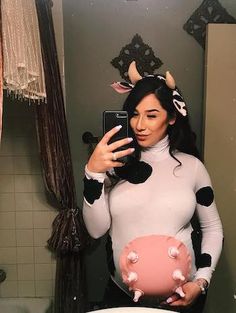 a woman is taking a selfie in the bathroom wearing a cow costume and holding a piggy bank