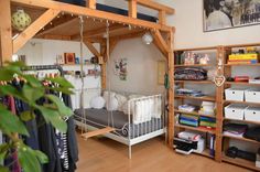 a bedroom with a bed and shelves filled with clothes on top of wooden flooring