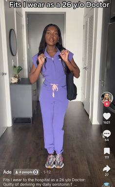 a woman in purple scrubs is walking down the hallway with her hand on her hip