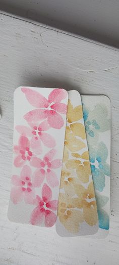 three coasters with watercolor flowers on them sitting on a white cabinet door handle