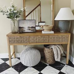 a wooden table topped with a basket next to a mirror